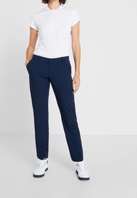 Marinenbyxor med slim fit, tillverkade av lätt material, matchade med en enkel vit kortärmad skjorta och vita skor.