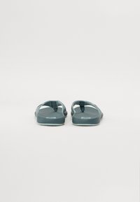Flip-flops med en teal gummistropp og såle, med teksturert fotseng og en glatt bunn. Minimalistisk design, uten synlige logoer eller mønstre.