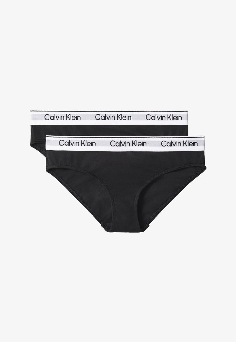 Kaksi mustaa Calvin Klein naisten alushousua valkoisella elastisella vyötärönauhalla, jossa mustat Calvin Klein -logot.