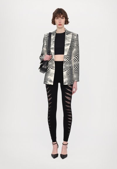 Zebra-print blazer med strukturerede skuldre, cropped sort top og ripped sorte leggings. Afsluttet med spidse sorte hæle og en lille taske.