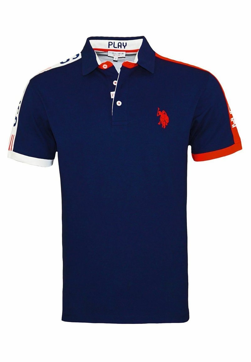 Polo bleu marine avec accents rouges et blancs sur les manches, logo joueur de polo brodé en rouge sur la poitrine et texte "PLAY" à l'intérieur du col.