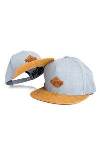 Cap featuring a gray denim crown and a tan suede brim, with a branded leather patch on the front. Snapback closure at the back.