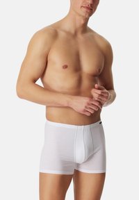 Boxer-briefs en coton blanc avec un ajustement serré, taille élastique et un design avec poche à l'avant. Texture lisse, style simple, sans motifs ni accents.