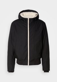 Veste noire à capuche avec doublure en polaire blanche, fermeture éclair sur le devant, poignets et bas côtelés, présentée sur fond blanc.