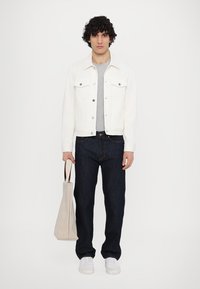 Valge denim jakk halli T-särgi, tume siniste teksade ja valgete tossudega. Hoiab kerge beeži käekotti, millel on pruunid sangad.
