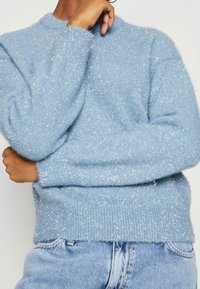 Hellblaue, flauschige Sweater mit metallischen Akzenten, Rundhalsausschnitt und gerippten Bündchen. Warmer Stoff, entspannte Passform, kombiniert mit Denim.