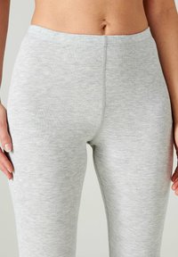Leggings a coste grigi chiaro con vita alta, caratterizzati da una texture liscia e cuciture lungo la parte anteriore e posteriore per una maggiore struttura.
