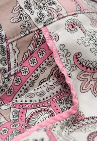 Stof met ingewikkelde paisley- en bloemmotieven in roze, zwart en beige. Randen hebben contrasterende roze stiksels. Zachte textuur.