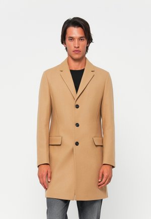Abrigo de mezcla de lana beige con solapa de muesca, tres botones negros y dos bolsillos laterales; silueta ajustada y textura suave.