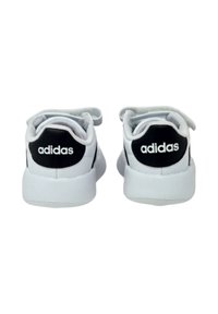 Scarpe sportive bianche con dettagli neri, dotate di un collo imbottito, fodera in tessuto testurizzato e logo "adidas" sul tallone.