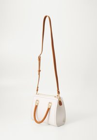 Borsa a mano in pelle bianca con design strutturato, tracolla marrone, dettagli in metallo dorato e chiusura superiore con zip.