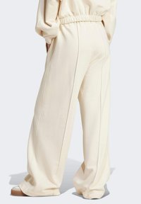 Pantaloni a gamba larga color crema con vita elastica, tasche laterali e dettagli cuciti lungo le gambe. Realizzati in un tessuto morbido e liscio.