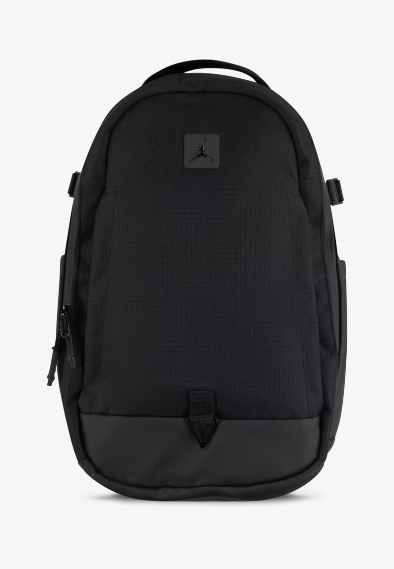 Mochila preta feita de tecido durável com um acabamento texturizado. Apresenta um emblema, bolsos laterais com fecho e um fundo reforçado.