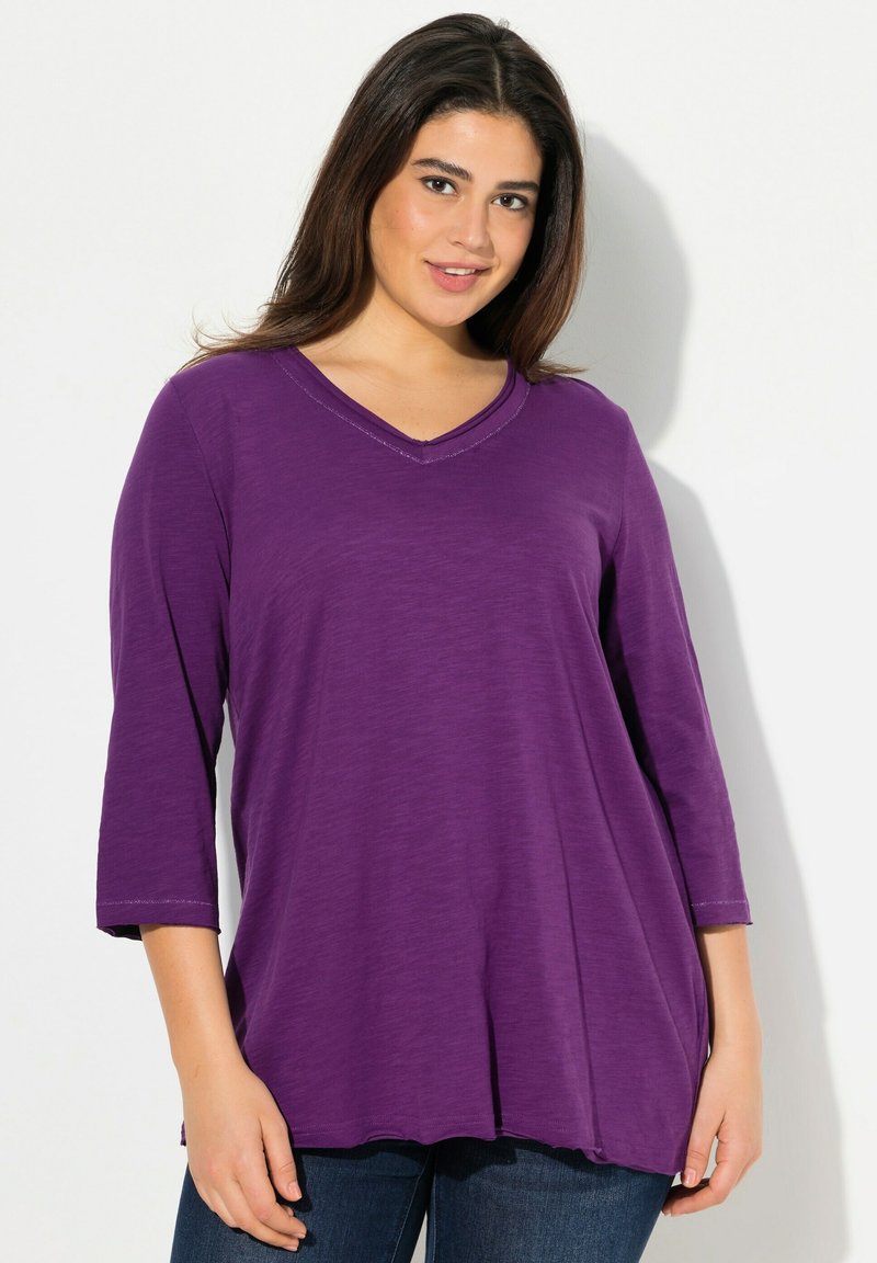 Lila, leichtes V-Ausschnitt-Oberteil mit Dreiviertelärmeln, lockerer Passform und subtiler Textur. Der Saum fällt unter die Hüften.
