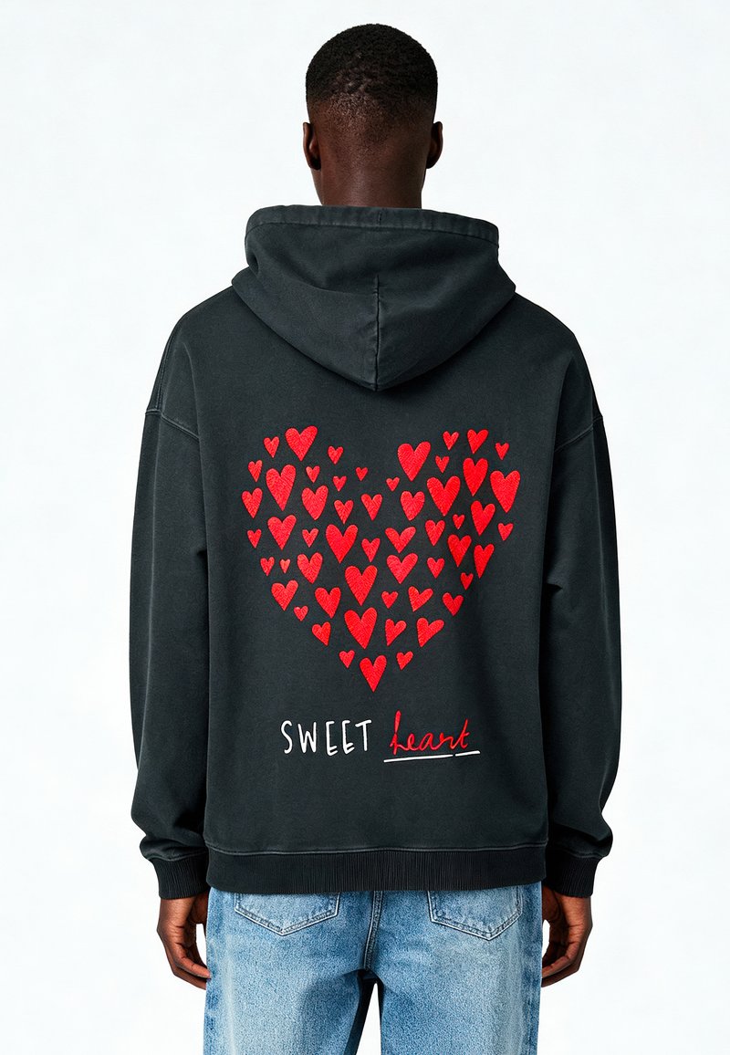 Felpa nera con cappuccio caratterizzata da un grande design a cuore rosso composto da cuori più piccoli, con il testo "SWEET heart" in bianco e rosso sul retro.
