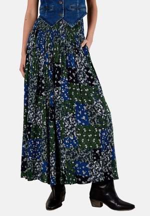 Falda maxi floral con diseño de patchwork en verde, azul y negro, con cintura fruncida y bolsillos laterales. Combina con un chaleco de mezclilla y botas.
