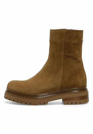 Botas de tobillo de ante marrón con punta redondeada, suela gruesa y cremallera lateral. Presentan una textura suave y detalles de costura sutil.