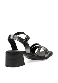 Sandalias negras de tacón con un diseño de tira texturizada, un tacón bloque y acentos metálicos decorativos en las correas del tobillo y frontal.