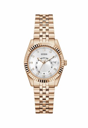 Montre Guess dorée avec un cadran argenté, des marqueurs d'heure en diamants et un affichage de la date, maintenue par un bracelet en métal.