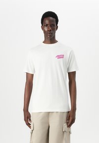 White cotton t-shirt featuring a pink "SANTA CRUZ" graphic on the left chest, short sleeves, and a crew neckline.