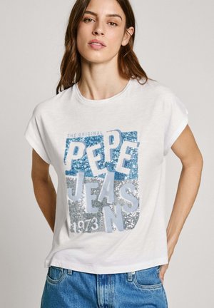 T-shirt en coton blanc avec un graphique en sequins multicolores contenant du texte. Le design inclut des accents bleus et argentés, ainsi que des manches retroussées.