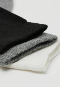 Trzy pary skarpetek w kolorze czarnym, szarym i białym. Wykonane z miękkiego, teksturowanego materiału z prążkowanymi mankietami i prostym wzornictwem.