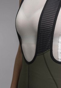 Mesh sports top featuring a black ribbed accent, white mesh panel, and fitted olive green bodice. Designed for moisture management and breathability.