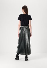 Top negru cu mânecă scurtă, asortat cu o fustă maxi plisată de un gri metalic, având un elastic la talie și o textură strălucitoare.
