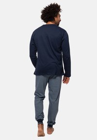 Marineblaues Langarmshirt kombiniert mit grauen Jogginghosen, die über gerippte Bündchen und eine entspannte Passform verfügen. Baumwollmischgewebe mit weicher Textur.