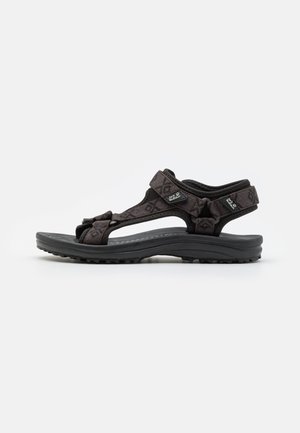Black sandal with patterned fabric straps, adjustable at the ankle, featuring a cushioned sole and textured rubber outsole for grip.