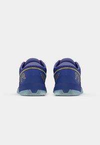 Scarpe atletiche viola con una parte superiore testurizzata, accenti blu e una suola traslucida. Il tallone presenta il logo TYR in oro.