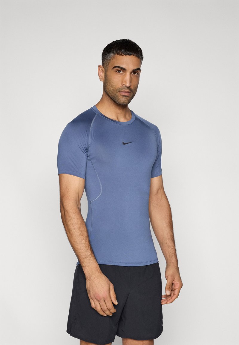 Εφαρμοστό μπλε αθλητικό μπλουζάκι από ύφασμα που απομακρύνει την υγρασία, με κοντά μανίκια και μαύρο λογότυπο Nike στο στήθος. Σετ με μαύρο σορτς.