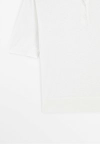 Polo blanc à manches courtes avec trois boutons, ourlets des manches côtelés et ceinture côtelée sur fond blanc.