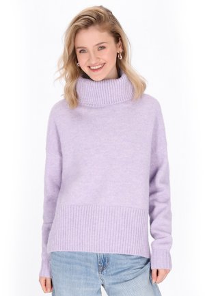Pull à col roulé violet clair avec des poignets et un ourlet côtelés, fabriqué dans un matériau doux. Associé avec un jean bleu clair.
