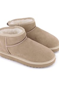Botas de tobillo de ante beige con un suave forro de lana, punta redondeada y suela de goma texturizada. Presenta un puño doblado y costuras reforzadas.