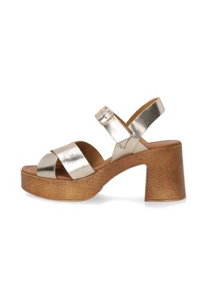 Metallic gold heeled sandals with a platform, featuring two wide straps and an ankle strap with a buckle, set on a textured wood-like base.