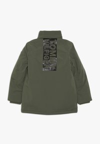 Veste vert olive avec un col montant, fermeture éclair et un logo noir imprimé verticalement dans le dos. Texture lisse et coupe droite.