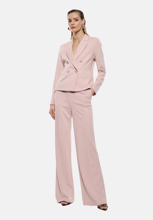 Completo su misura rosa chiaro con giacca doppiopetto e pantaloni a gamba larga, caratterizzato da una texture liscia e un design strutturato.