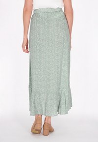 Groene maxi-jurk met bloemenpatroon, met een gerimpelde zoom, elastische taille, lichtgewicht stof, en gecombineerd met tan blokhakken.