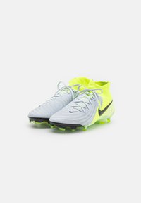 Scarpe da calcio in grigio chiaro con una parte superiore testurizzata e colletto giallo neon. Presentano dettagli neri e tacchetti verdi sulla suola.