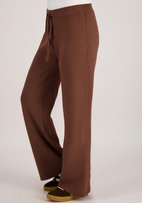 Bruine broek met wijde pijpen en een gestructureerde stof, voorzien van een elastische tailleband en een trekkoord. Eenvoudig ontwerp zonder zichtbare patronen of metalen details.