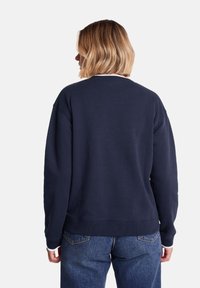 Navy blue sweatshirt with a crew neck, ribbed hem, and cuffs. Soft texture, relaxed fit, and contrasting white inside neckline.