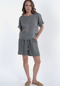 Grijze linnen top met korte mouwen en bijpassende shorts. De top heeft een ontspannen pasvorm en opgerolde mouwen. Beide hebben een gladde, gestructureerde afwerking.