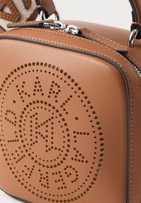 posetă din piele marron, cu formă pătrată, având detalii cu logo perforat și accesorii din metal argintiu pentru închiderea cu fermoar.