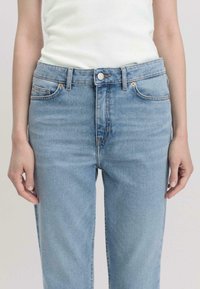 Lichtblauwe denim jeans met een hoge taille, voorzien van vijf zakken, een knoopsluiting en subtiele vervaging. Glad textuur, recht model.