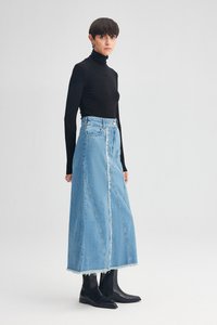 Svetlo modra denim maxi krila z razfrušenim robom, visokim pasom in vertikalnimi šivi, kombinirana z črnim puloverjem s štirimi vrati in črnimi gležnjarji.