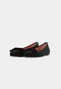 Paire de ballerines noires à bouts arrondis avec des nœuds décoratifs en corde torsadée sur un fond blanc uni.