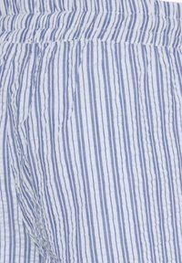 Tissu léger à rayures verticales blanches et bleues, probablement un vêtement, avec une taille élastique froncée.