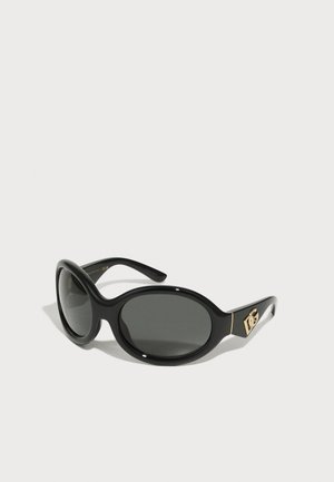 Occhiali da sole neri a forma ovale con lenti scure. Presentano una montatura in plastica lucida e accenti dorati del logo sui lati. Design leggero.