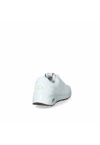 Scarpa sportiva bianca con tomaia in materiale sintetico liscio, dettagli testurizzati, colletto imbottito e suola in gomma con un logo in accento discreto.